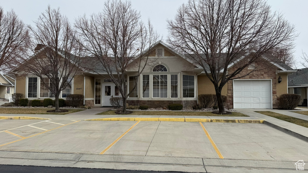 View of front facade featuring stone siding, stucco siding, and uncovered parking