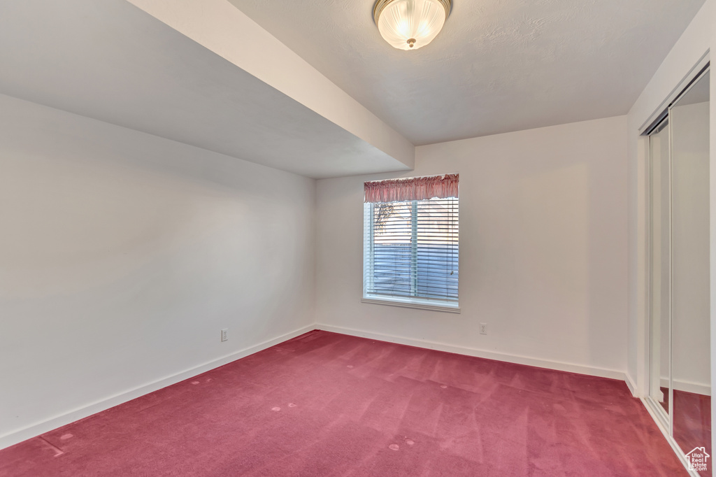 Empty room with baseboards and dark colored carpet