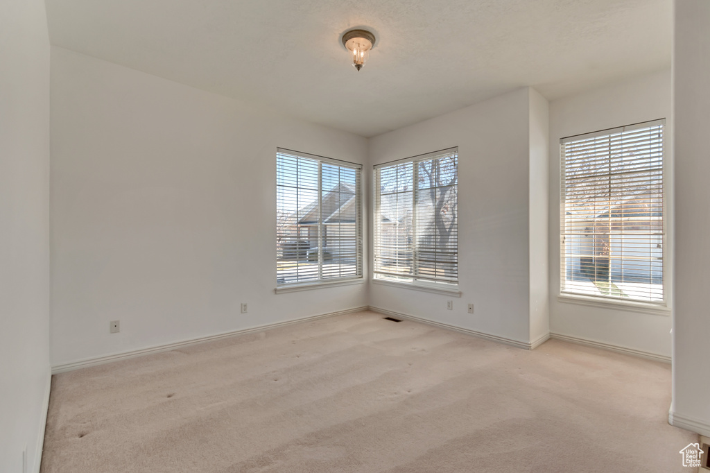 Empty room with light colored carpet and baseboards