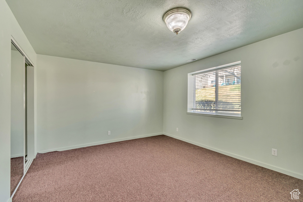 Unfurnished bedroom with baseboards, carpet, and a textured ceiling