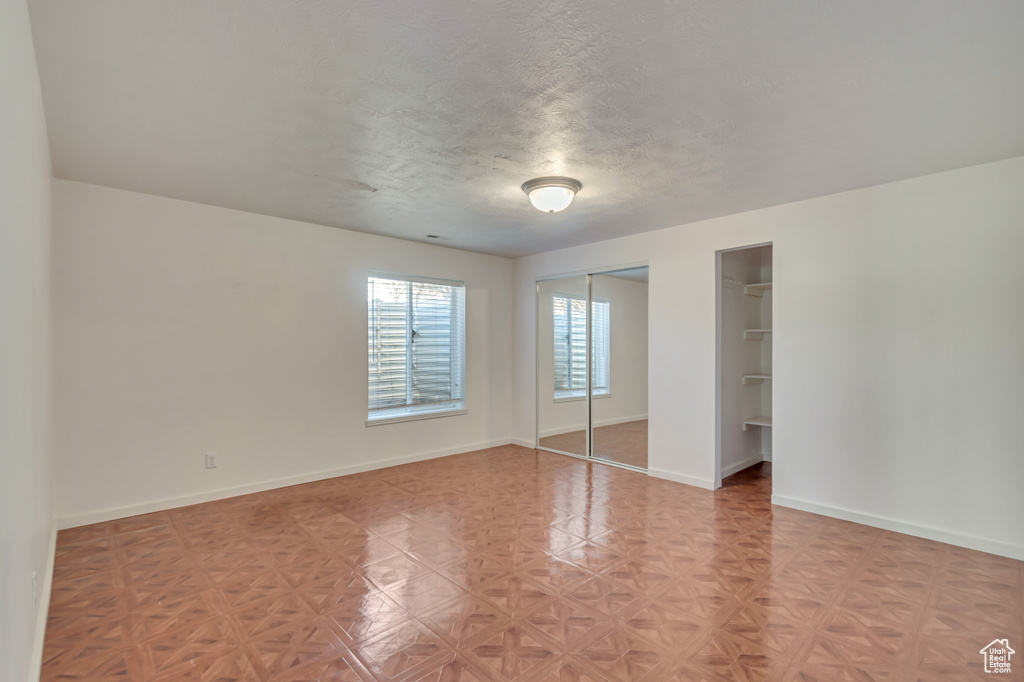 Unfurnished bedroom with baseboards, multiple closets, and a textured ceiling