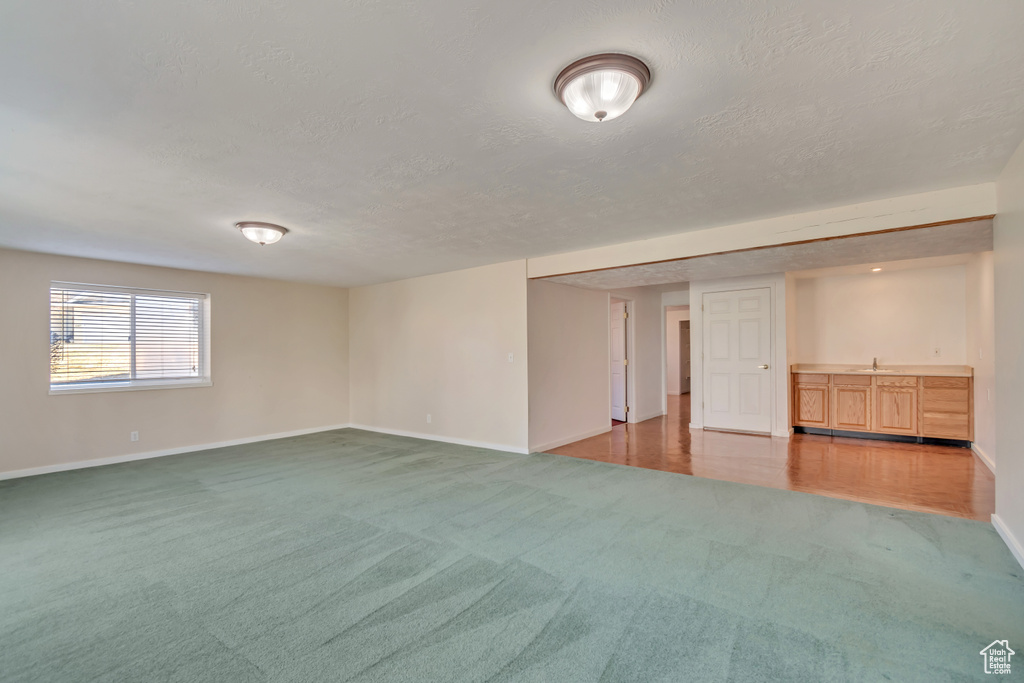 Spare room with baseboards, a textured ceiling, a sink, and light colored carpet