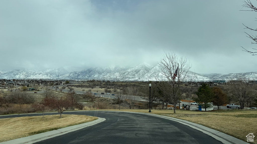 View of street with a mountain view, street lights, and curbs