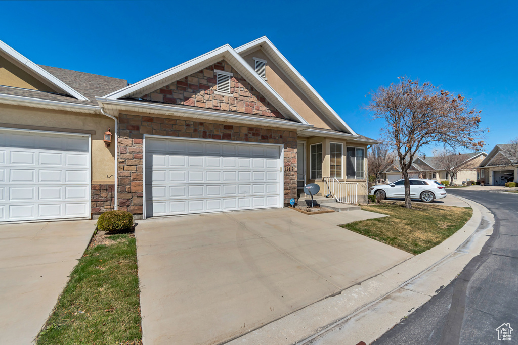 View of front of property with driveway, stone siding, and a garage