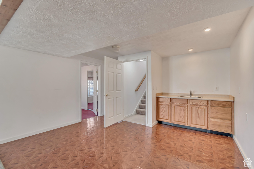 Interior space featuring a sink, baseboards, stairs, and a textured ceiling