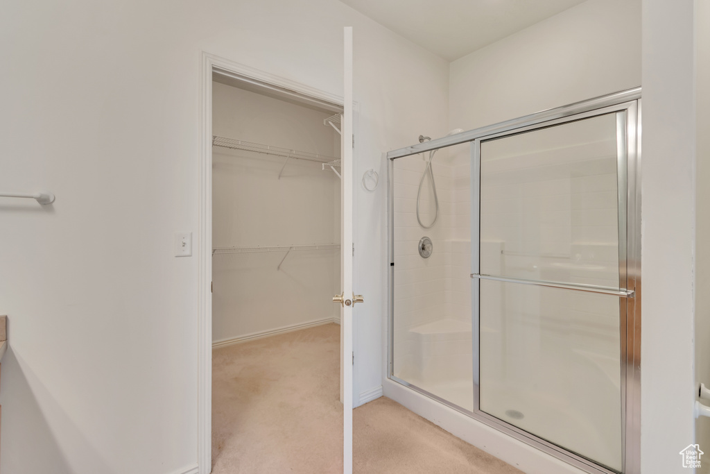 Bathroom featuring baseboards, a spacious closet, and a shower stall
