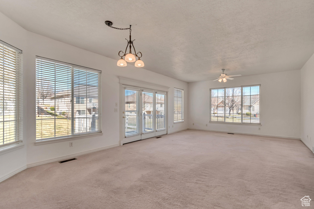 Carpeted empty room featuring a ceiling fan, a textured ceiling, baseboards, and visible vents