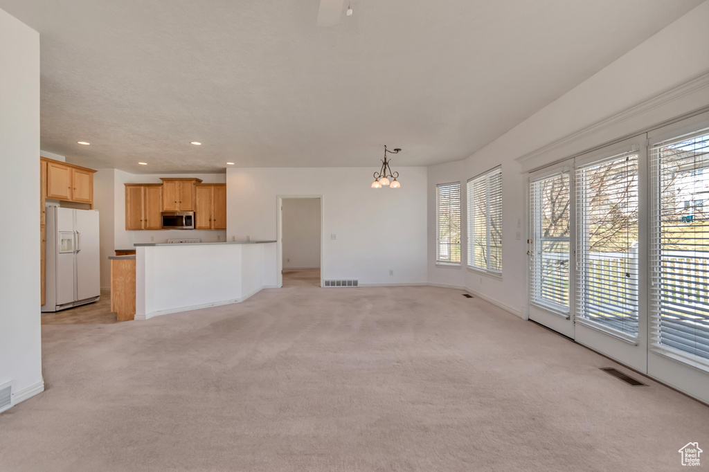 Unfurnished living room featuring light colored carpet, visible vents, baseboards, and recessed lighting
