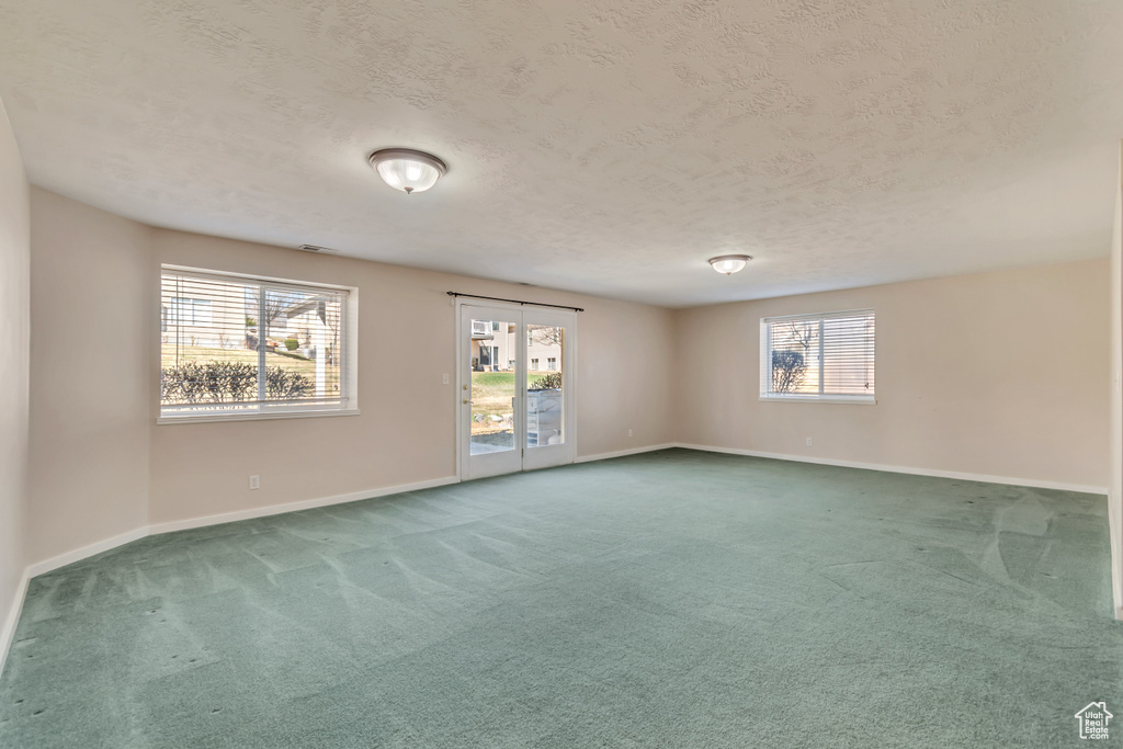 Carpeted empty room featuring baseboards and a textured ceiling
