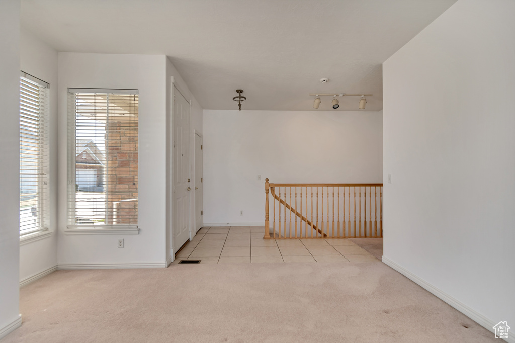 Spare room featuring baseboards, visible vents, rail lighting, and carpet floors