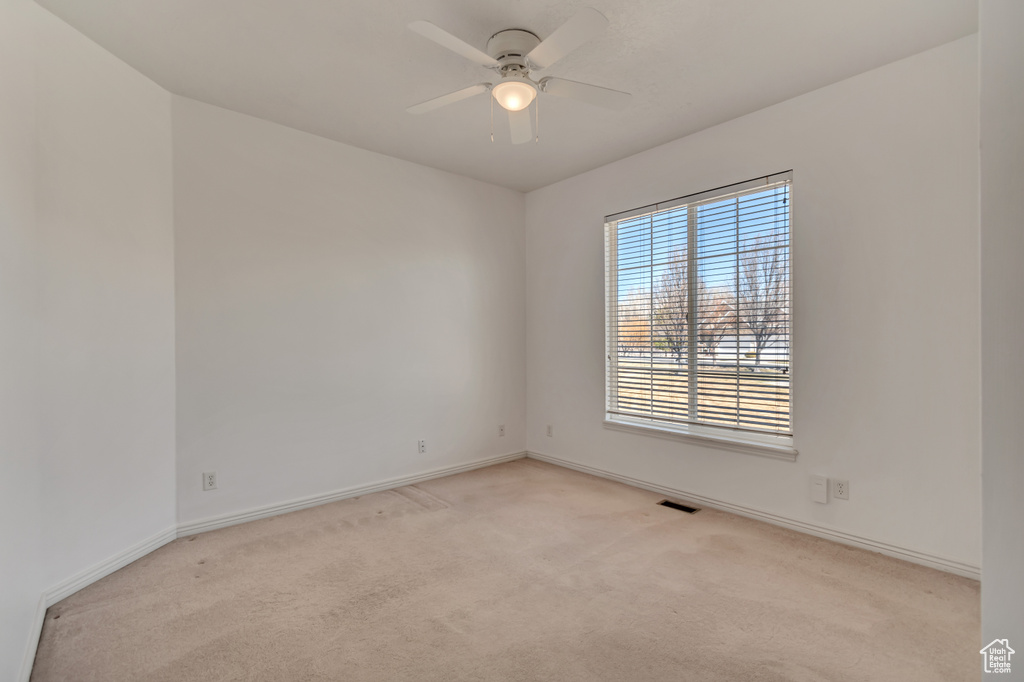 Empty room with visible vents, baseboards, light colored carpet, and ceiling fan