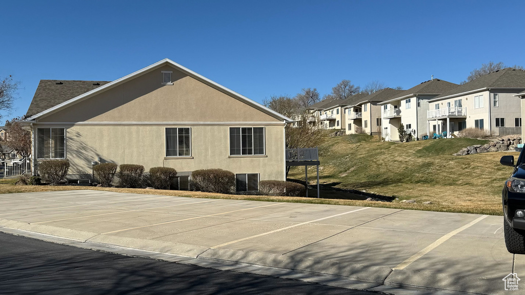 View of home\\\'s exterior featuring stucco siding, uncovered parking, a lawn, and a residential view