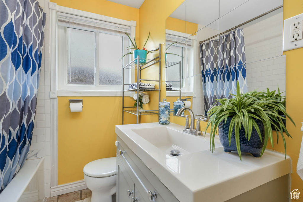 Bathroom with toilet, vanity, baseboards, and shower / bath combo with shower curtain