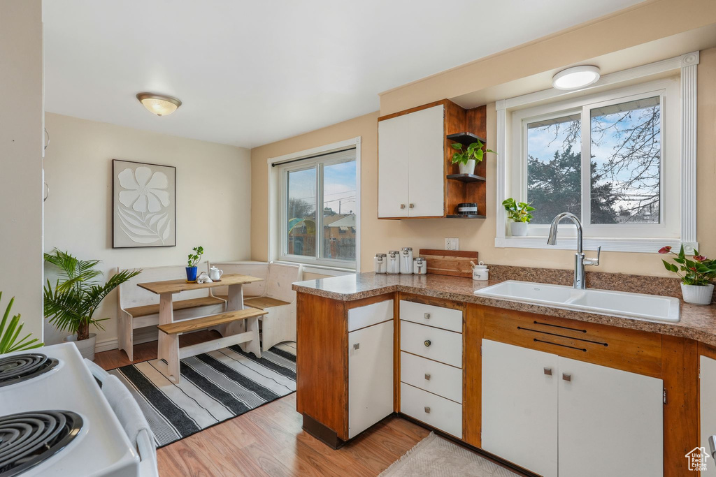 Kitchen with white cabinets, white electric range, light wood finished floors, a sink, and open shelves