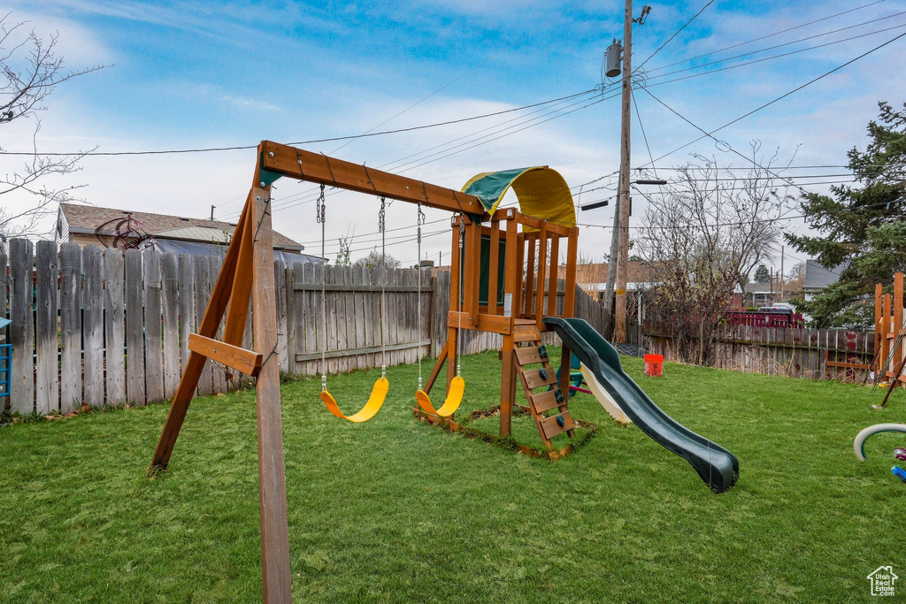 View of play area with a fenced backyard and a yard