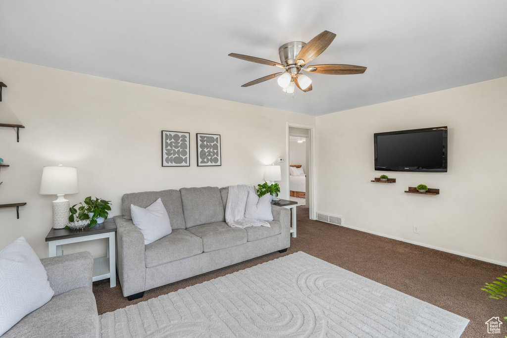 Carpeted living room with baseboards, ceiling fan, and visible vents
