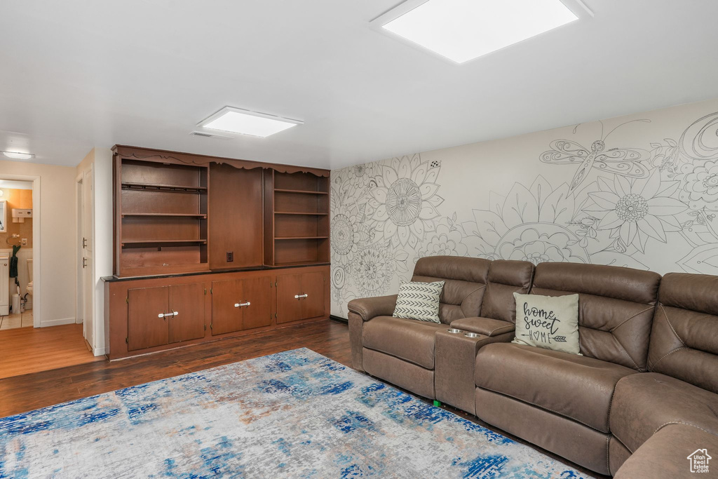 Living room featuring dark wood-type flooring, baseboards, wallpapered walls, and an accent wall