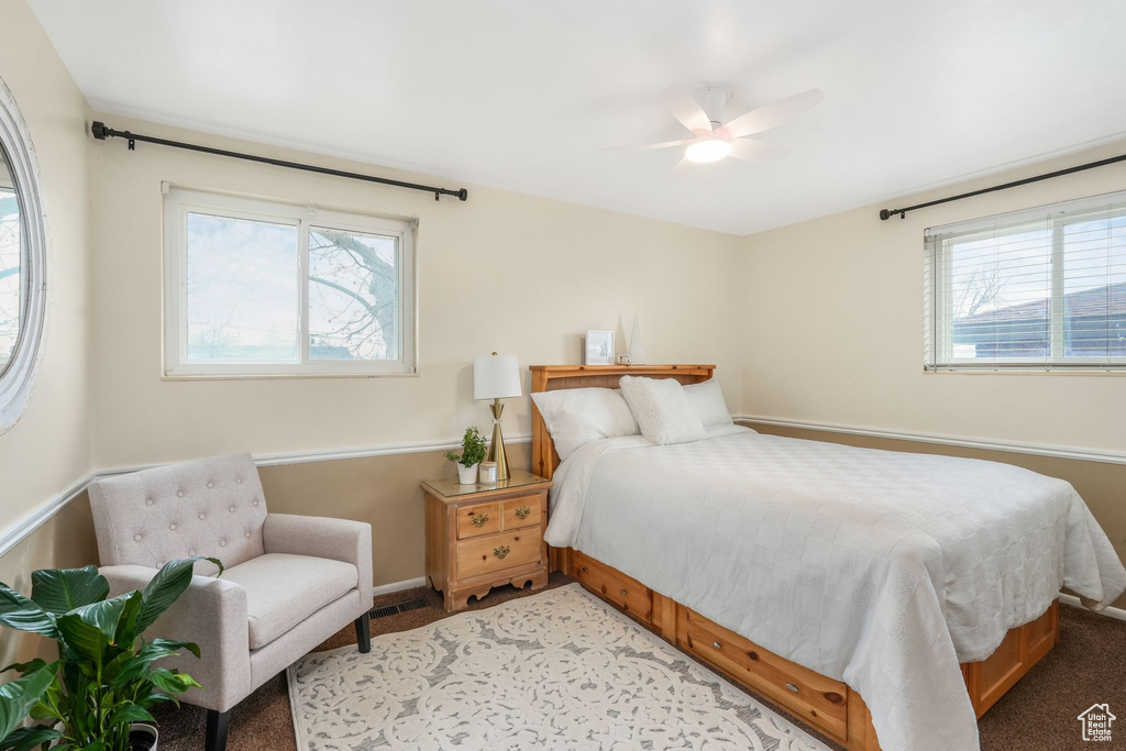 Bedroom featuring light carpet, multiple windows, and ceiling fan