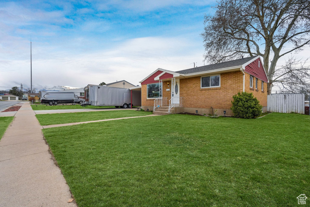 View of front facade featuring driveway, brick siding, crawl space, and a front yard