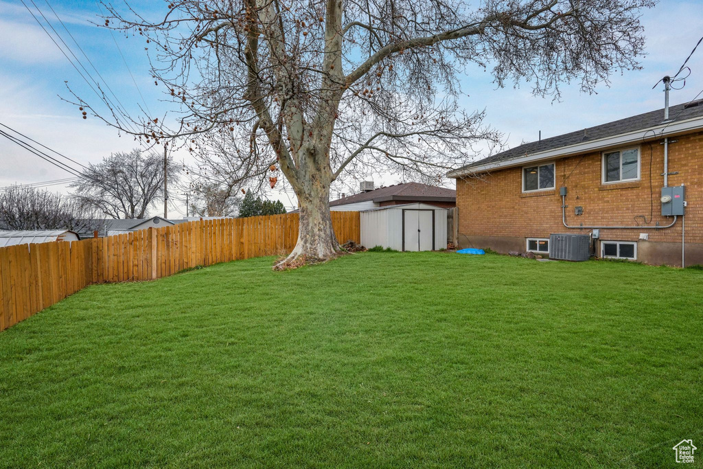 View of yard with a fenced backyard, cooling unit, an outdoor structure, and a storage shed