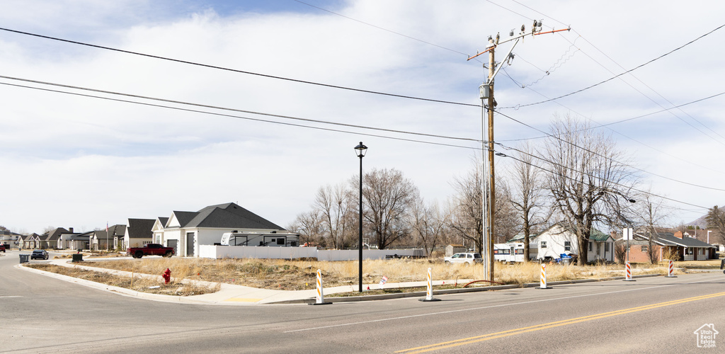 View of asphalt road with a residential view, sidewalks, curbs, and street lights