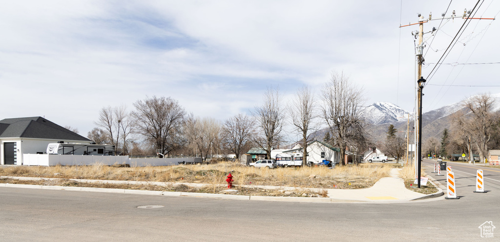 View of asphalt street featuring sidewalks, a mountain view, and curbs