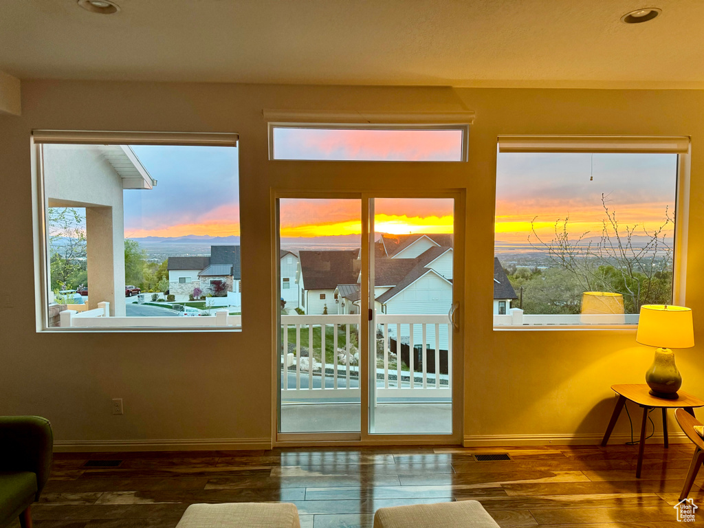 Doorway to outside featuring baseboards, wood finished floors, and a healthy amount of sunlight