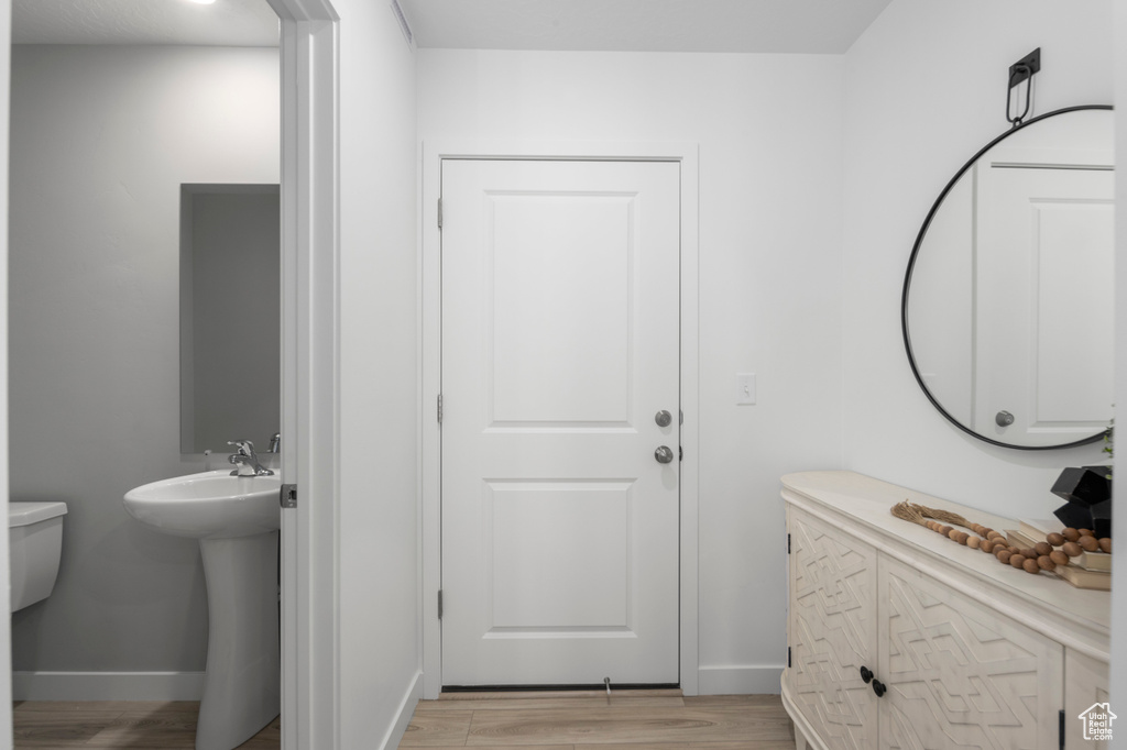 Half bathroom featuring a sink, baseboards, and wood finished floors