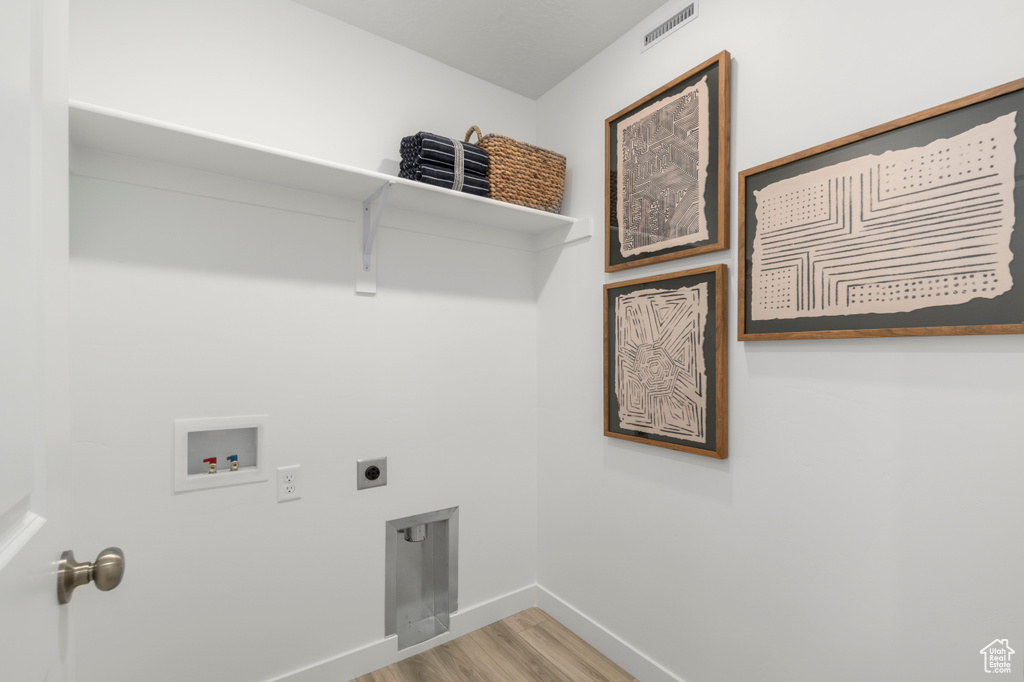 Laundry area with hookup for an electric dryer, hookup for a washing machine, baseboards, visible vents, and laundry area