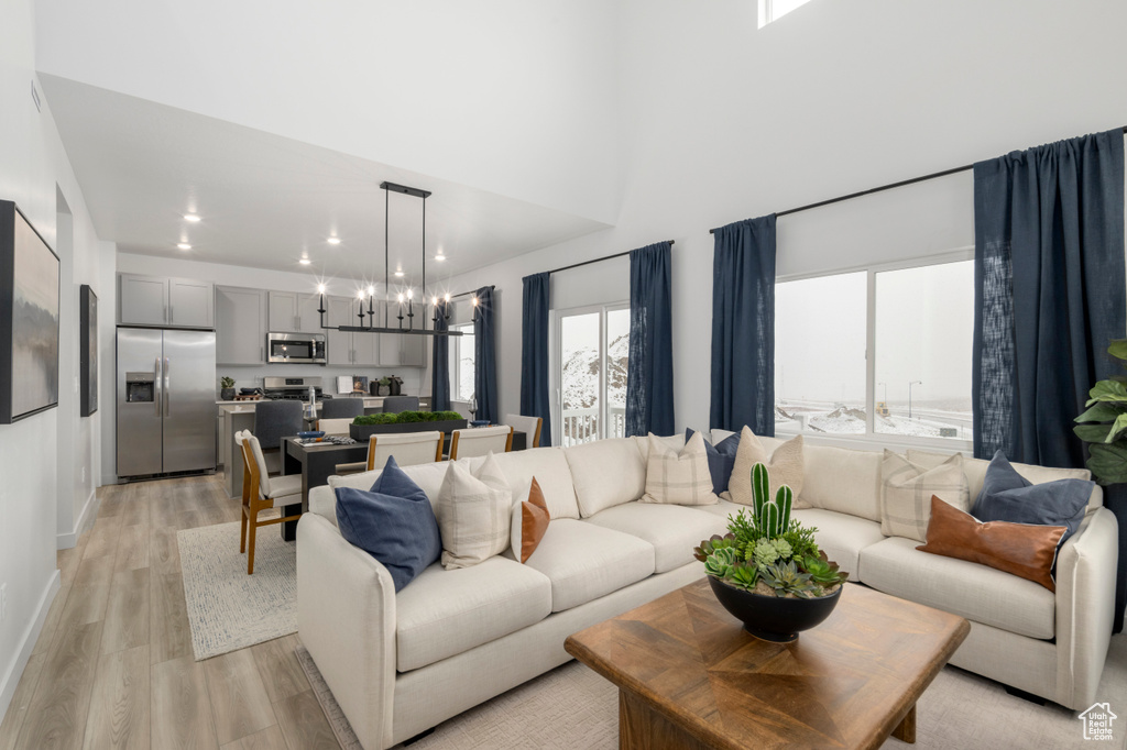 Living room featuring a towering ceiling, baseboards, light wood finished floors, and recessed lighting