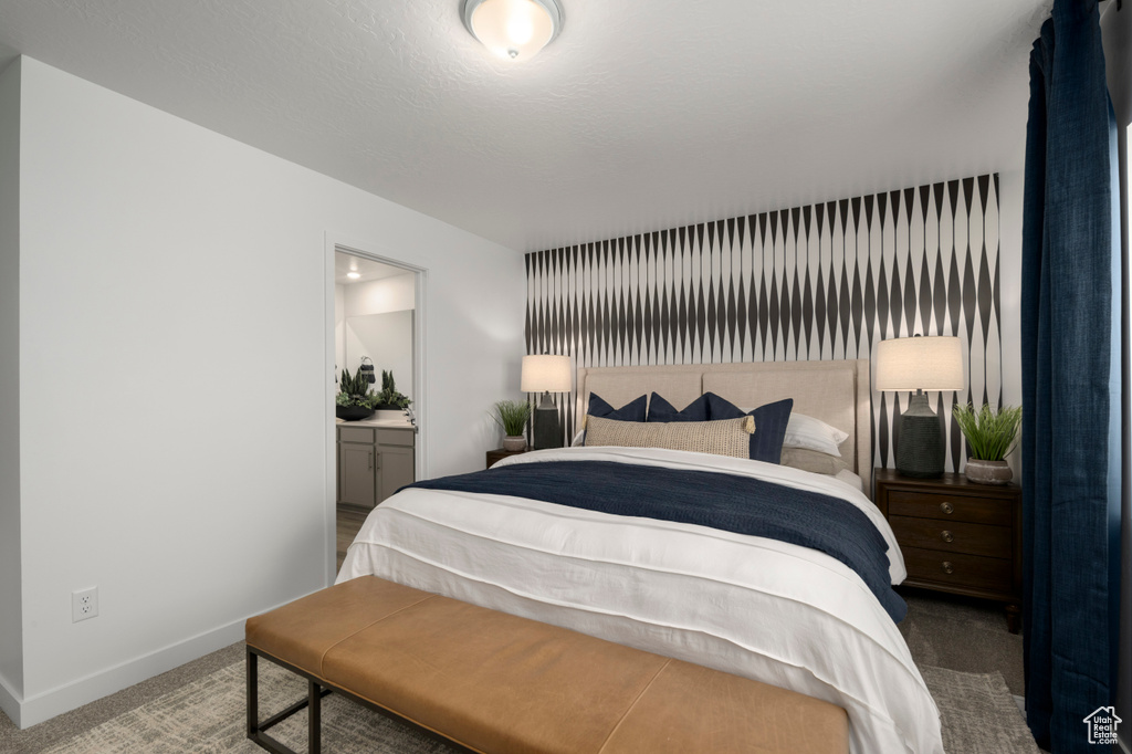 Carpeted bedroom with connected bathroom and baseboards