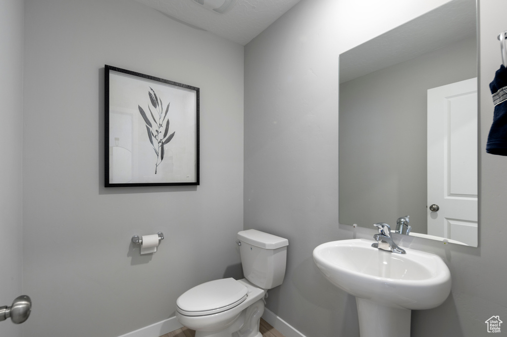 Bathroom with baseboards, toilet, and a sink
