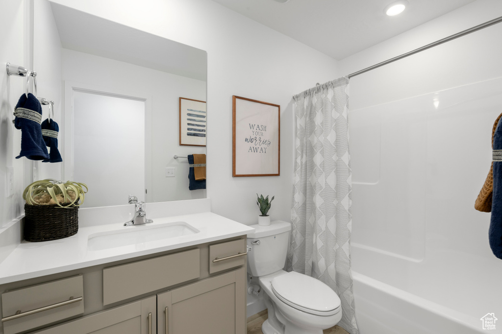 Full bath with toilet, shower / tub combo with curtain, and vanity