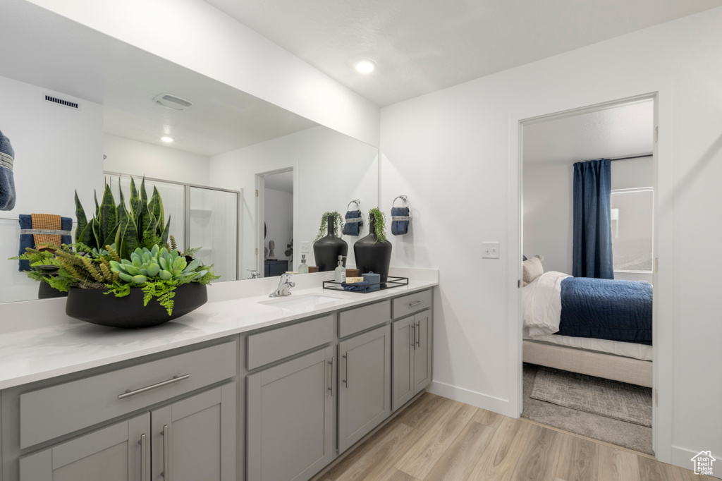 Full bath featuring vanity, a shower stall, connected bathroom, and wood finished floors