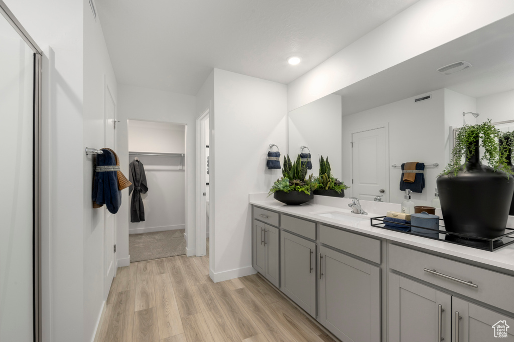 Bathroom with visible vents, baseboards, wood finished floors, vanity, and a spacious closet