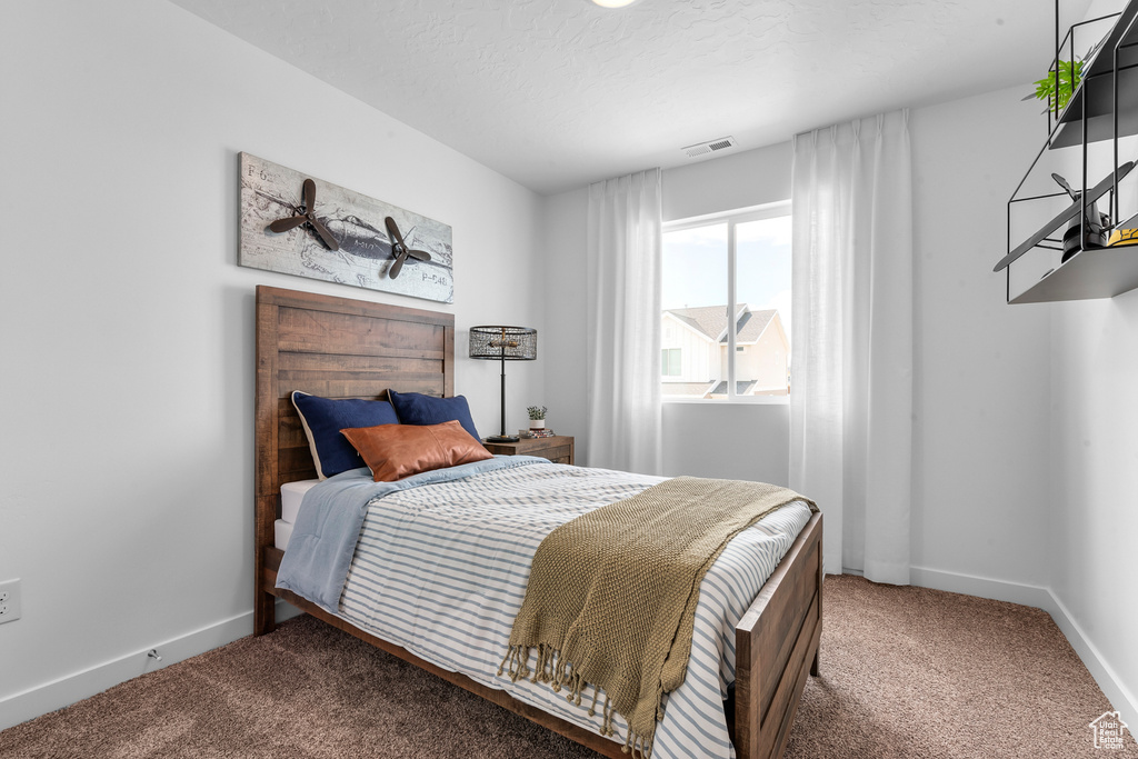 Carpeted bedroom featuring baseboards, visible vents, and a textured ceiling