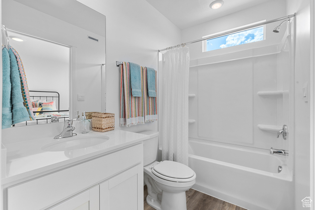 Full bathroom featuring toilet, shower / bath combo with shower curtain, vanity, and wood finished floors