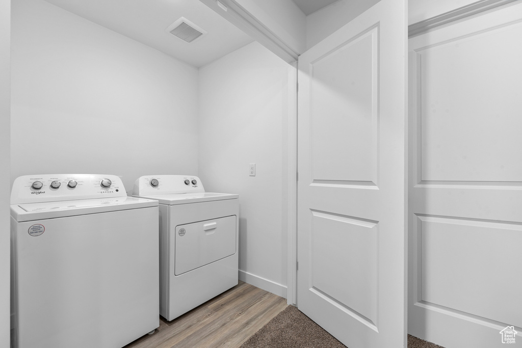 Washroom featuring washing machine and dryer, visible vents, laundry area, and light wood-type flooring