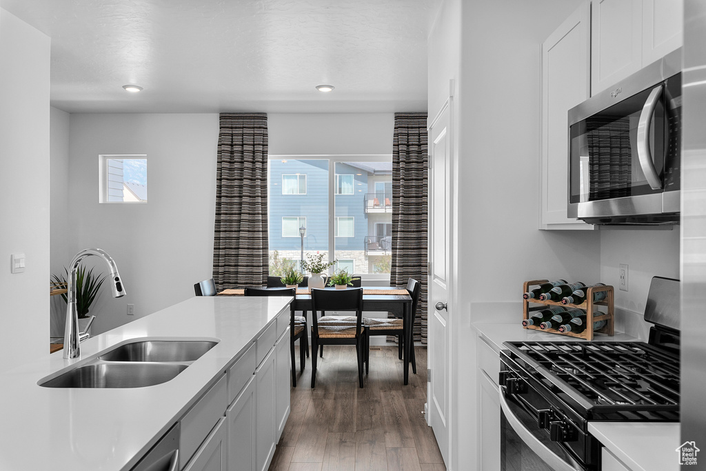 Kitchen with light countertops, a sink, light wood-style flooring, stainless steel microwave, and range with gas stovetop