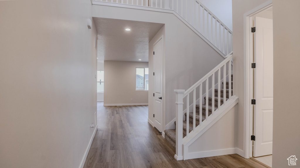 Stairs with baseboards, wood finished floors, and recessed lighting