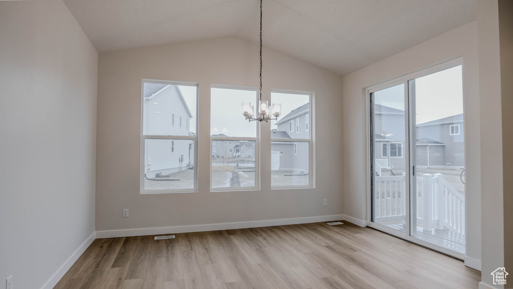 Unfurnished dining area with baseboards, lofted ceiling, a notable chandelier, and light wood finished floors