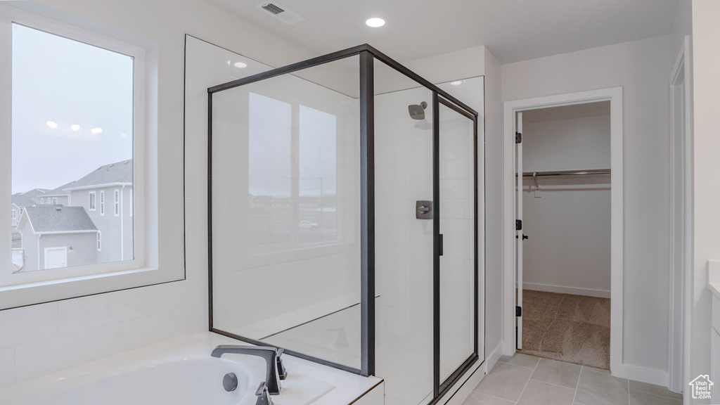 Bathroom with tile patterned floors, a shower stall, a spacious closet, a bath, and visible vents
