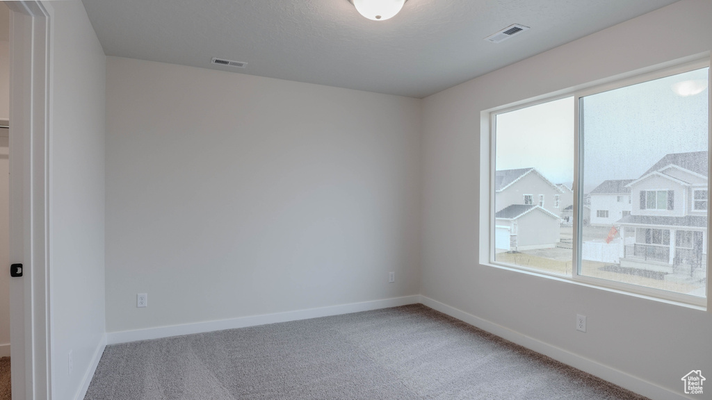 Unfurnished room featuring baseboards, visible vents, carpet floors, and a healthy amount of sunlight