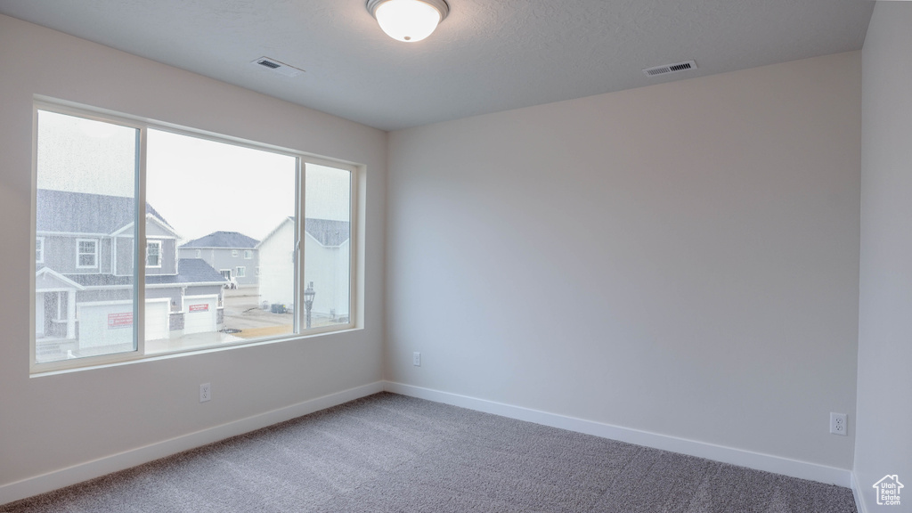Carpeted empty room featuring baseboards and visible vents