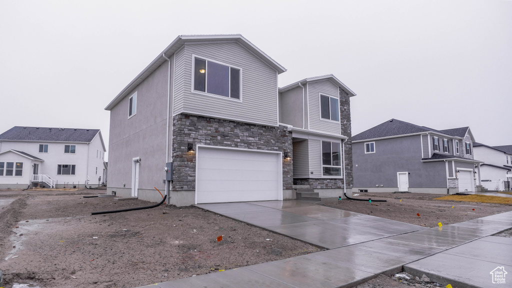 View of front of house with driveway, an attached garage, and stone siding