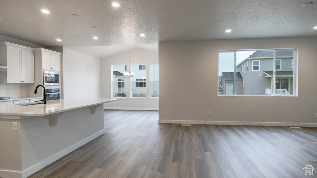 Kitchen with light countertops, an inviting chandelier, a sink, white cabinets, and appliances with stainless steel finishes