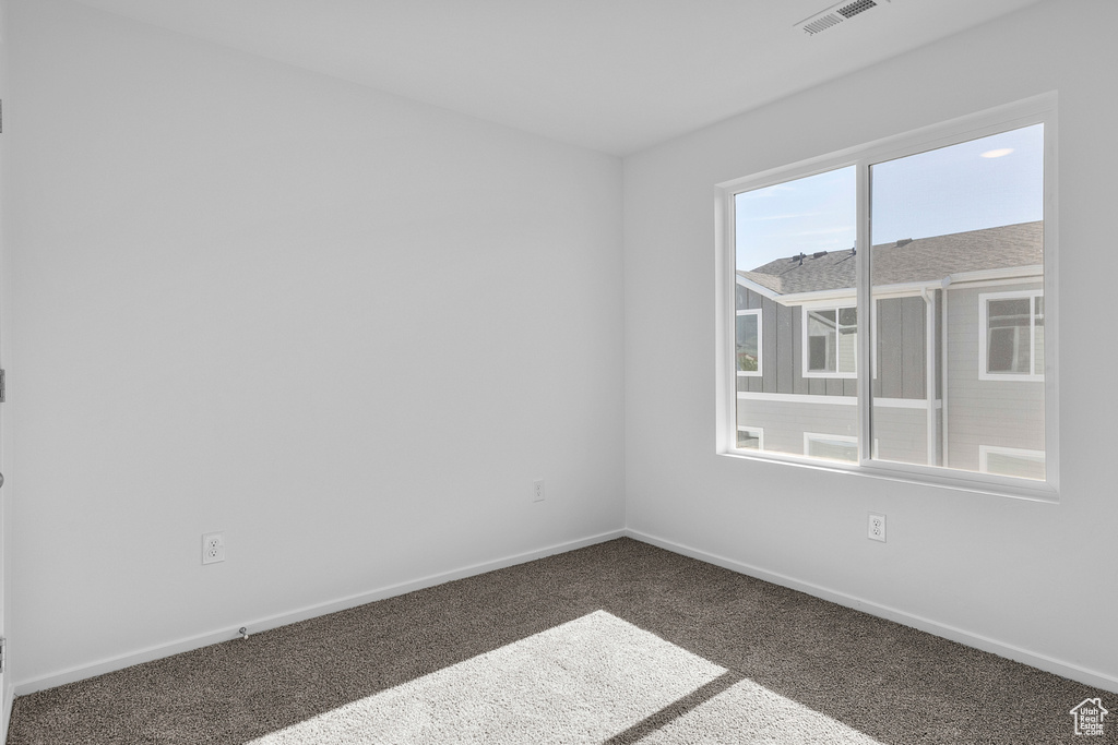Empty room with carpet flooring, baseboards, and visible vents