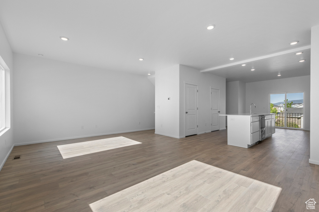 Unfurnished living room with wood finished floors, a sink, baseboards, and recessed lighting