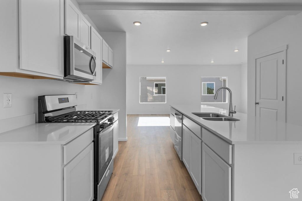 Kitchen featuring a sink, light countertops, light wood-style flooring, and appliances with stainless steel finishes