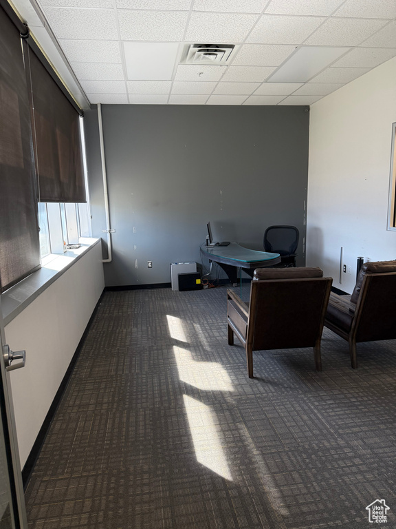 Office area featuring baseboards, carpet floors, visible vents, and a drop ceiling